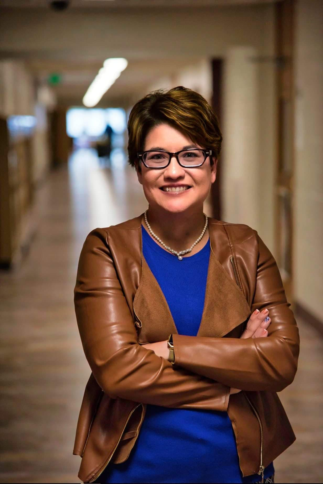 Linda standing in a hallway with arms crossed, smiling.